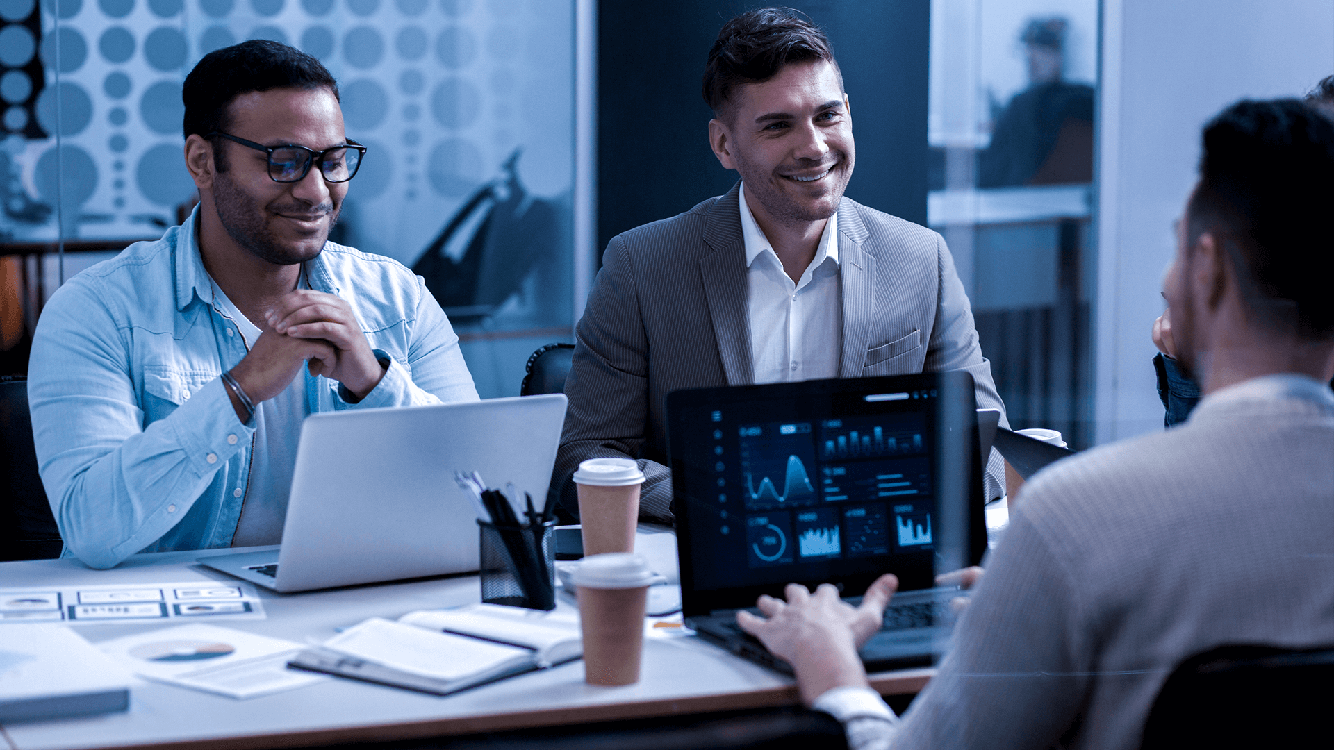 Professionals working at computers with coffee, symbolizing software outsourcing in Latin America.