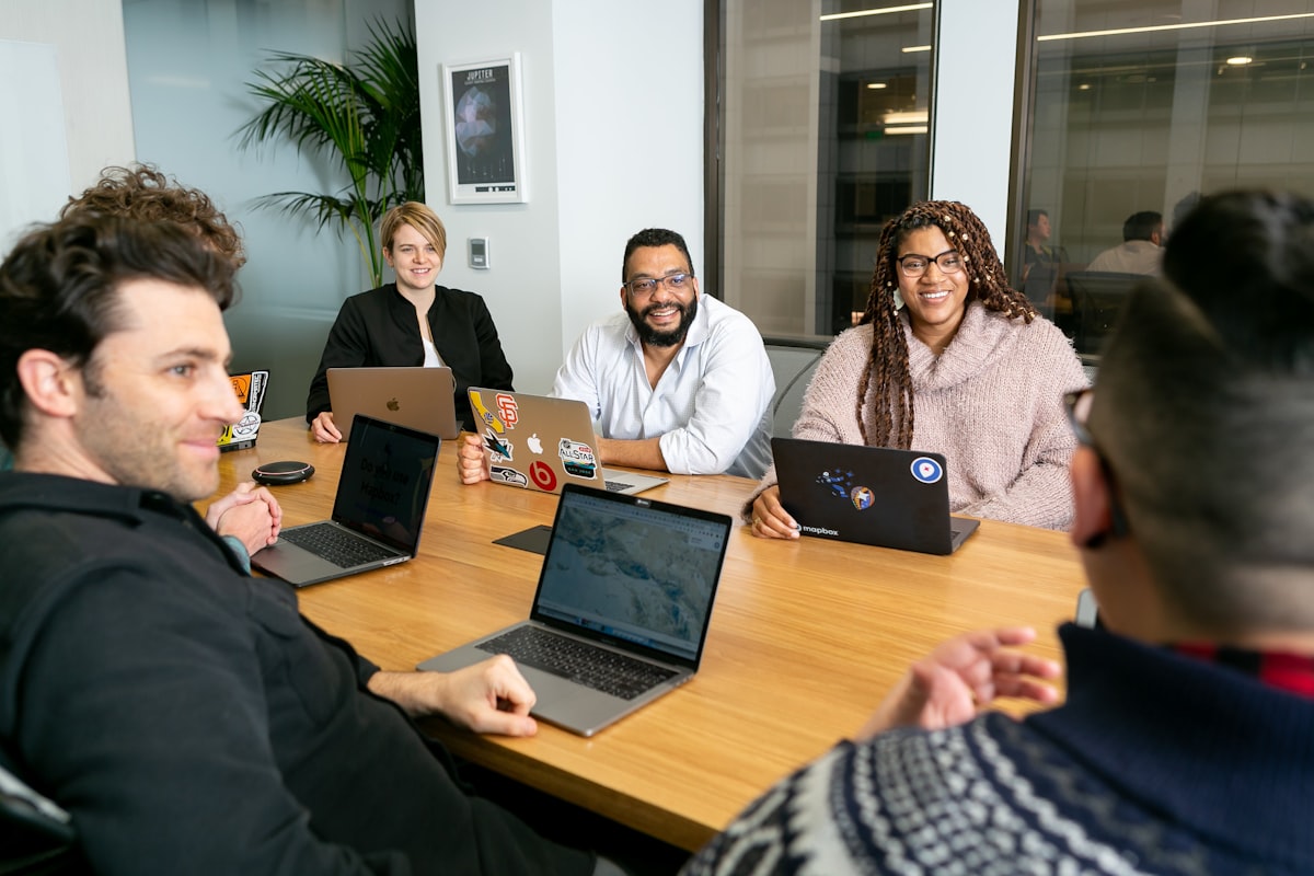 Diverse engineering team of four professionals working on laptops in a collaborative meeting, representing nearshore software development
