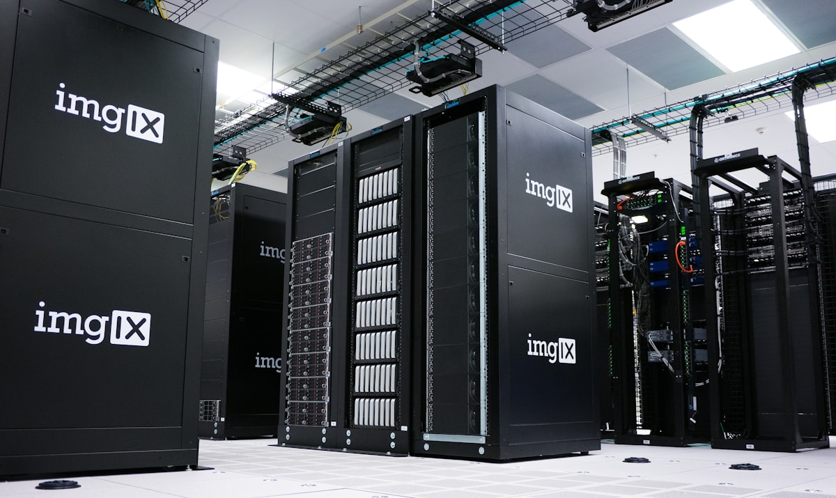 Rows of dark server racks with illuminated status lights lining an aisle in an enterprise data center